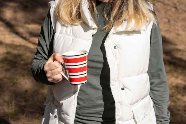 Die Hand der Frau hält eine Tasse heißen Tee, während sie sich im Freien entspannt