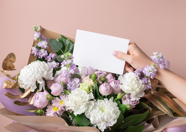 Die Hand der Frauen, die leere Papierkarte und schönen Blumenstrauß hält