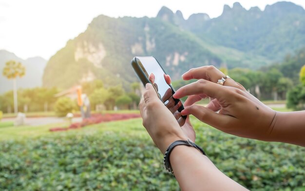 Die Hand der Frauen entspannt sich in den Ferien, sie spielt mit dem Handy auf dem Rasen im Garten.