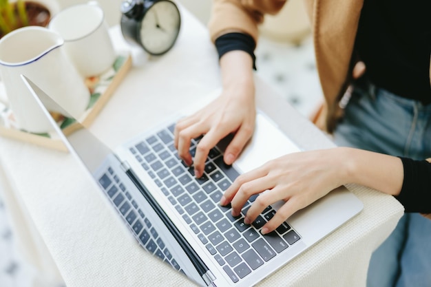 Die Hand der jungen asiatischen Geschäftsfrau verwendet einen Laptop, um online zu arbeiten und zu studieren Kleine Unternehmer