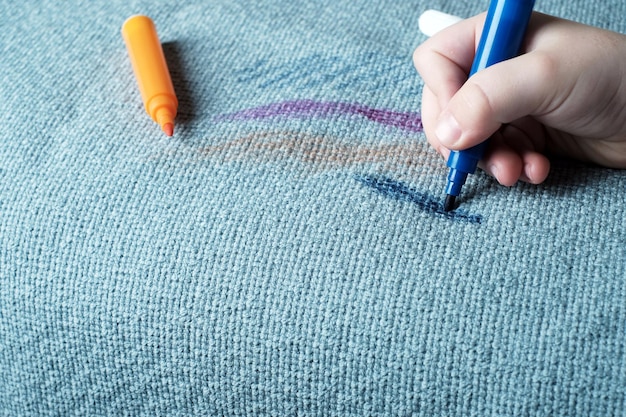 Foto die hand der kinder zeichnet einen rosafarbenen filzstift auf den stoff des sofas, der schmutzfleck des täglichen lebens zum waschen