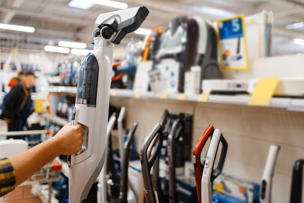 Die Hand der männlichen Person hält einen Staubsauger im Elektronikladen. Mann kauft elektrische Haushaltsgeräte im Markt