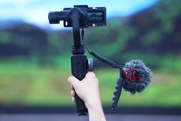 Foto die hand der person, die das ereignis auf einer videokamera mit einem stabilisator filmt. technologien und moderne geräte