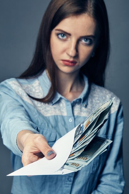 Die Hand der Person gibt ein Bestechungsgeld in Dollar. US-Dollar in der Hand. Frau bietet Geld auf einer dunklen Oberfläche. Ein Haufen amerikanisches Geld in der Hand auf einer dunklen Oberfläche.