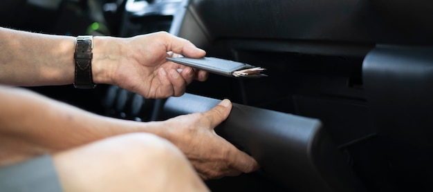 Die Hand der Person nimmt Brieftasche Bargeld und Kreditkarte aus dem Handschuhfach im Auto