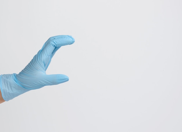 Die Hand des Arztes in einem blauen medizinischen Handschuh hält ein Objekt auf weißem Hintergrund. Kopieren Sie Platz, halten Sie ein beliebiges Objekt