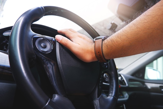 Die Hand des Fahrers drückt auf das Hupen des Lenkrads