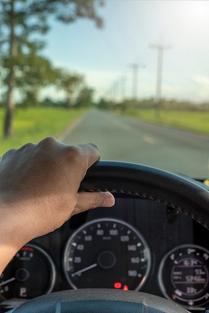 Die Hand des Fahrers hält das Lenkrad im Auto. vertikale Ansicht Reisekonzept