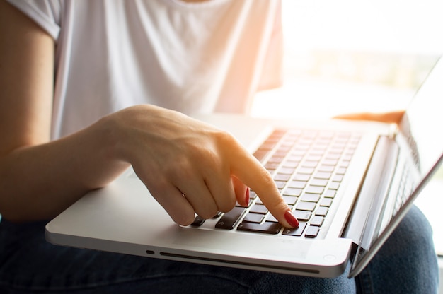 Die Hand des Mädchens tippt auf einer Laptoptastatur und drückt die Eingabetaste, Moment der Bestätigung, Nahaufnahme