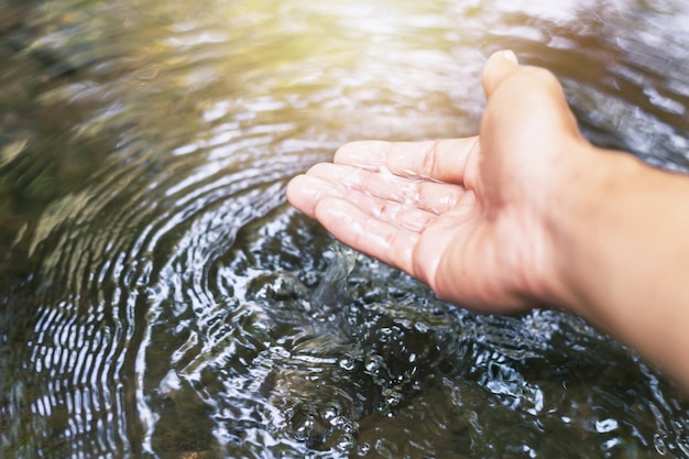 Die Hand des Mannes berührt Wasser inmitten der Natur