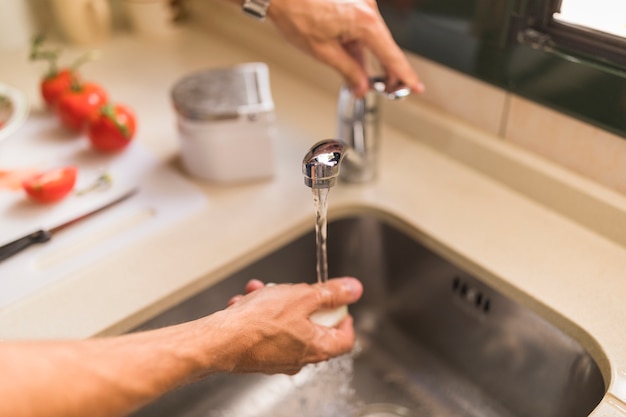 Die hand des mannes, die rettich in der wanne wäscht