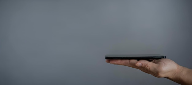 Die Hand des Mannes mit Smartphone-Bildschirm nach oben isoliert auf dunkelgrauem Hintergrund