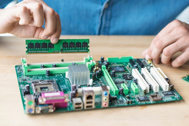 Die hand des technikers, die ram hält, motherboard reparierend