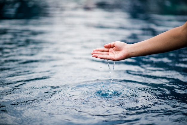 Die Hand, die das blaue Wasser berührt.