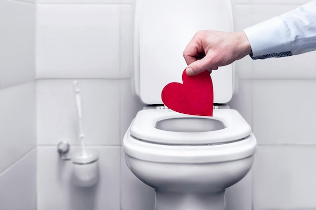 Die Hand, die das Herz in den Toilettenmüll wirft, ein Symbol für zerbrochene Liebe und Trennungsstreit ...