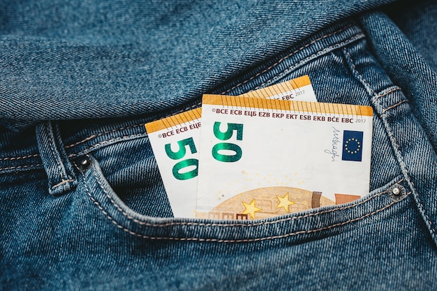 Die Hand, die Euro-Banknoten in eine Jeanstasche steckt