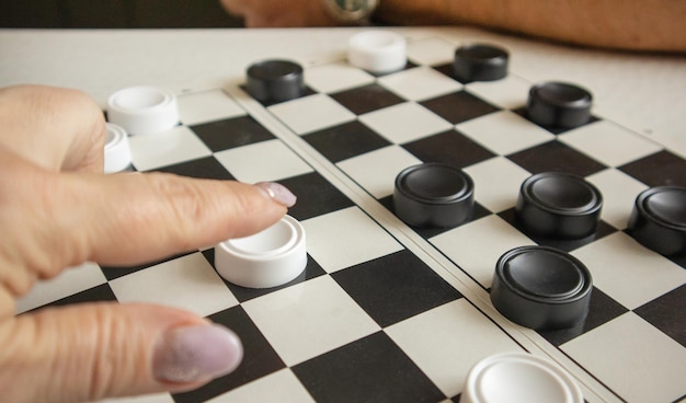 Die Hand einer Frau bewegt einen weißen Stein auf einem schwarz-weißen Spielfeld das Konzept von Hobbys und Heimspielen