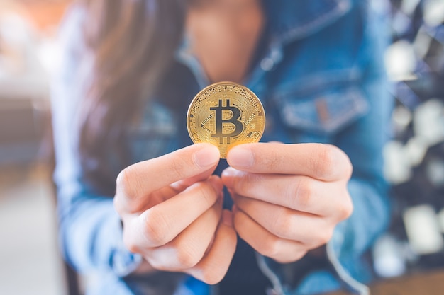 Die Hand einer Frau, die eine Währung, bitcoin hält.