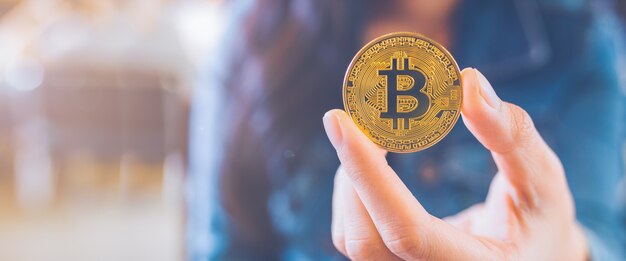 Die Hand einer Frau, die eine Währung, bitcoin hält.