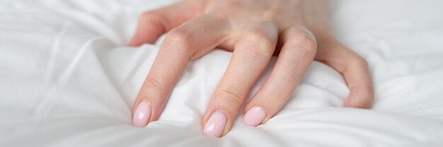 Die Hand einer Frau drückt eine Decke auf das Bett