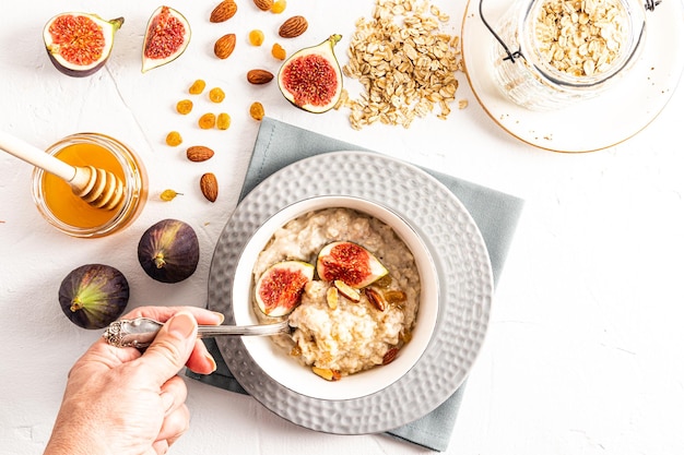 Die Hand einer Frau hält beim Frühstück einen mit Haferflocken gefüllten Löffel Haferflocken mit Obst in einer Schüssel gesunde Ernährung Detox