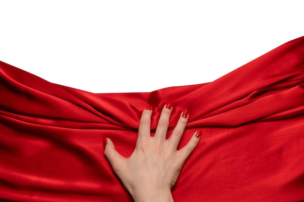 Die Hand einer Frau mit roten Nägeln versucht, einen roten Seidenstoff abzureißen