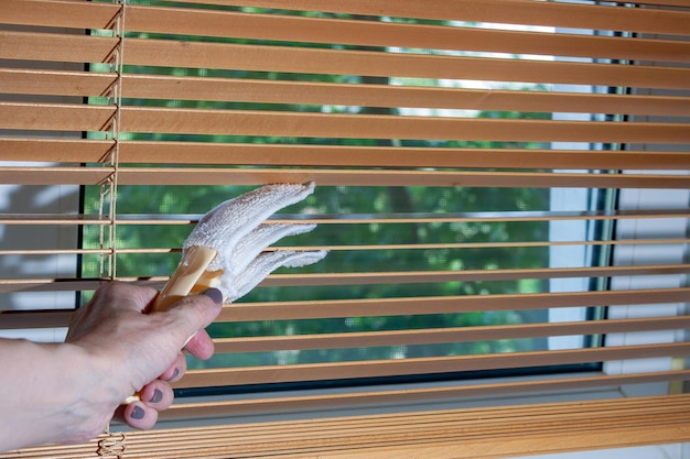 Foto die hand einer frau reinigt holzjalousien