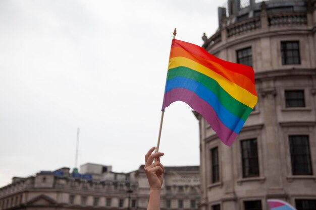 Die Hand einer Person, die eine Gay-Pride-Flagge schwenkt