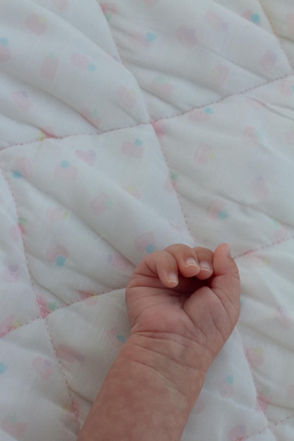 die Hand eines anmutigen zwei Monate alten Neugeborenen, das entspannt in seiner Krippe ruht