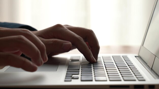 Die Hand eines Geschäftsmannes arbeitet an einem leistungsfähigen Laptop-Computer am Bürotisch, Nahaufnahme