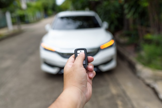 Die Hand eines Mannes drückt die Fernbedienung, um die Autotür zu verriegeln oder zu entriegeln.