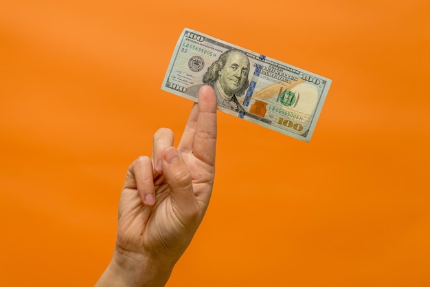 Die Hand eines Mannes hält Dollargeld isoliert auf orangefarbenem Hintergrund