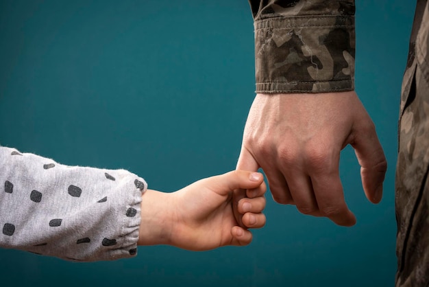 Die Hand eines Soldaten hält die Hand eines Kindes in Nahaufnahme Vater ist ein Mann des Militärs Ein Soldat und ein Kind