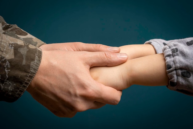 Die Hand eines Soldaten hält die Hand eines Kindes in Nahaufnahme Vater ist ein Mann des Militärs Ein Soldat und ein Kind