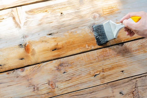 Die Hand hält den Pinsel aus lackiertem Holz. Hilft, die Produktarbeit schöner zu machen. Hilft, die Lebensdauer von Möbeln zu verlängern