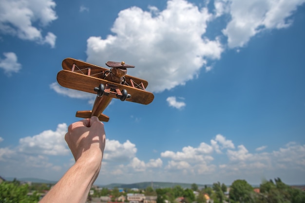 Die Hand hält ein Holzflugzeug über dem Land