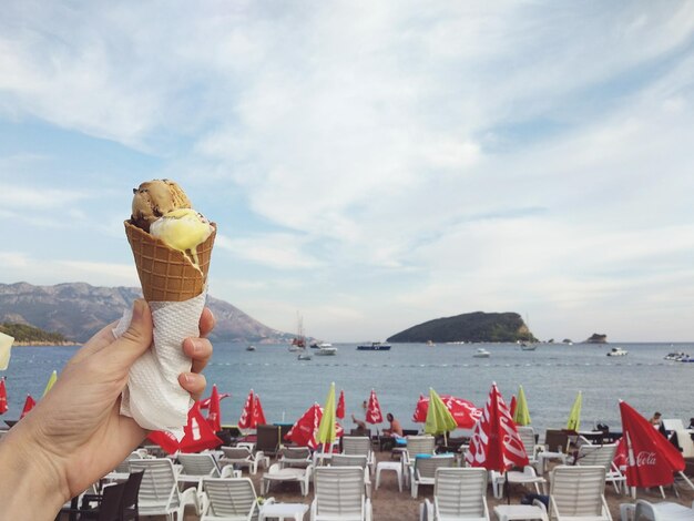 Foto die hand hält eis gegen das meer gegen den himmel am strand