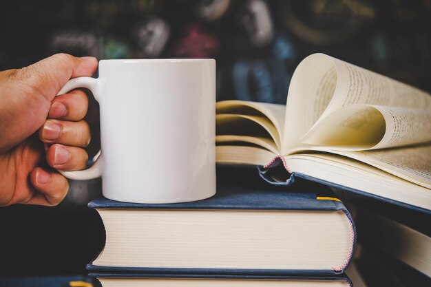 Die Hand hob den Becher auf das Buch im Klassenzimmer