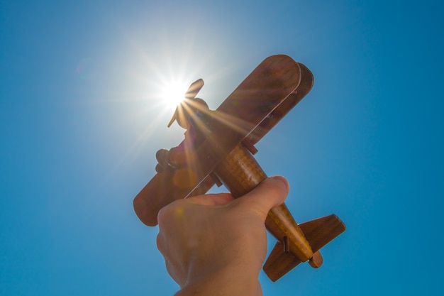 Die Hand mit einem Holzhobel auf dem Hintergrund der hellen Sonne