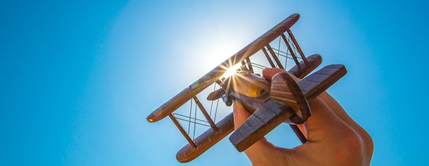 Die Hand startet ein Holzflugzeug auf dem Hintergrund der Sonne