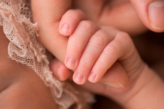 Die Hand und Finger eines Neugeborenen. Eltern halten die Finger ihres Neugeborenen mit ihren Händen. Foto in hoher Qualität