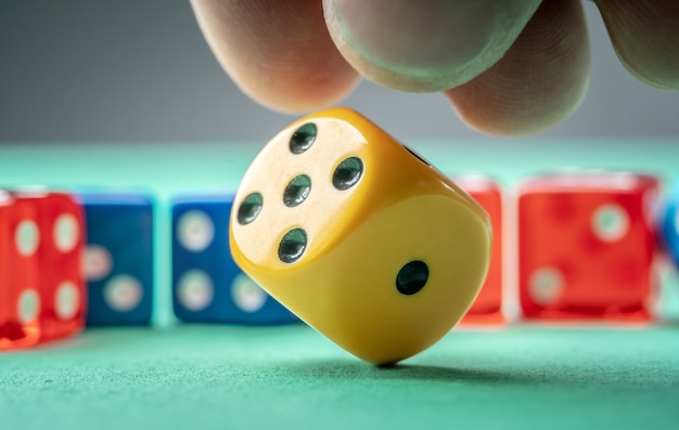 Foto die hand wirft gelbe würfel auf den grünen tisch. das konzept eines casinos und eine glückliche chance zu gewinnen