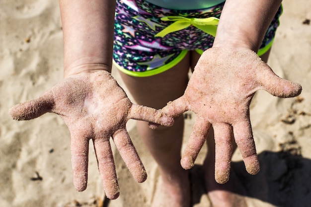 Die Handflächen des Kindes sind im Sand verschmutzt.