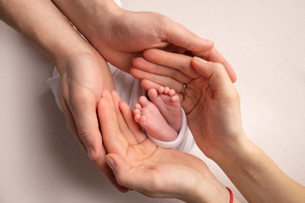 Die Handflächen des Vaters der Mutter halten den Fuß des neugeborenen Babys Füße des Neugeborenen auf den Handflächen der Eltern Studiofotografie eines Kindes 39 Zehen Fersen und Füße Konzept