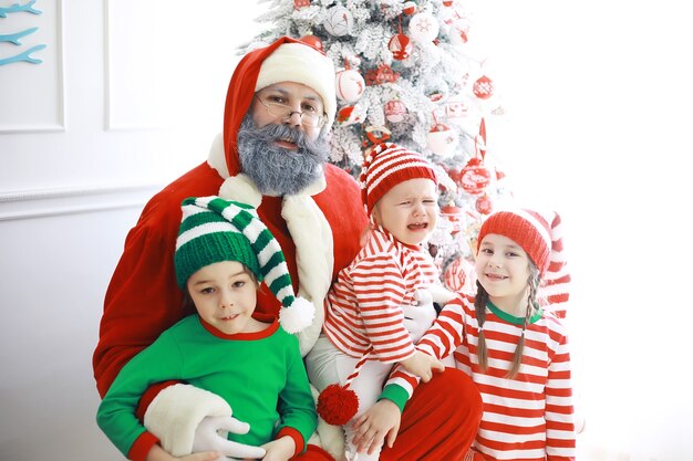 Die Helfer des Weihnachtsmanns. Süße Kinder in Weihnachtselfenkostümen in einem weihnachtlich dekorierten Raum. Zeit der Wunder. Geschenke vom Weihnachtsmann.