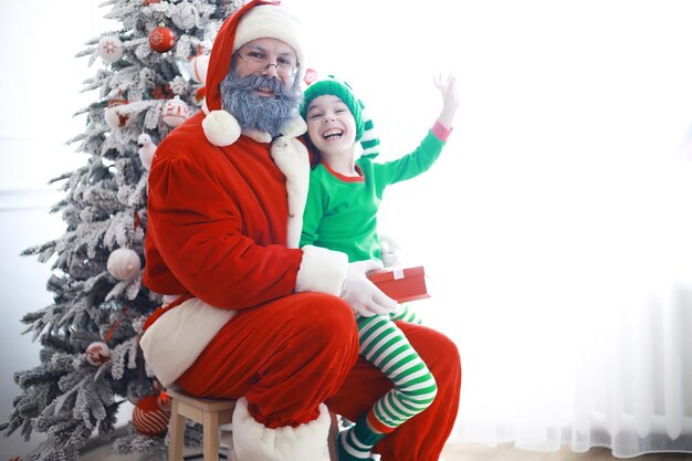 Die Helfer des Weihnachtsmanns. Süße Kinder in Weihnachtselfenkostümen in einem weihnachtlich dekorierten Raum. Zeit der Wunder. Geschenke vom Weihnachtsmann.