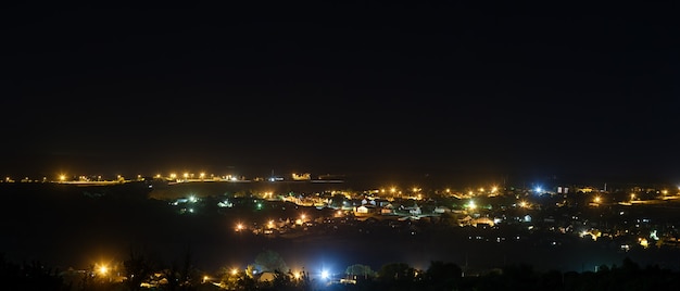 Die hellen Lichter der Straßen der Stadt am Nachthimmel. Panoramablick auf Wohngebiete.