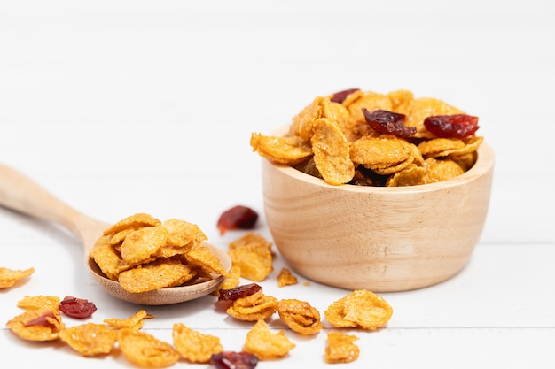 Die Holzschüssel mit Karamell-Cornflakes mit Rosinen auf weißem Hintergrund für gesundes Essen und Frühstückskonzept