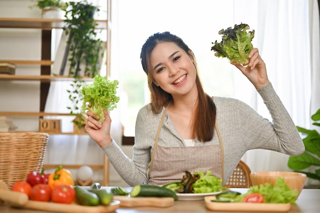 Die hübsche asiatische Frau bereitet gerne Zutaten für ihre gesunde grüne Salatschüssel zu