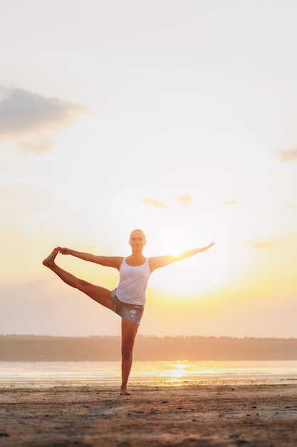 Die hübsche Frau macht Yoga bei Sonnenuntergang im Freien